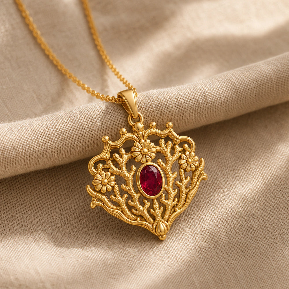 Ruby coral crown daisy pendant with an oval deep-red stone in a smooth bezel, raised daisy flowers, and branching coral-like openwork in an ornate frame. Gold finish.