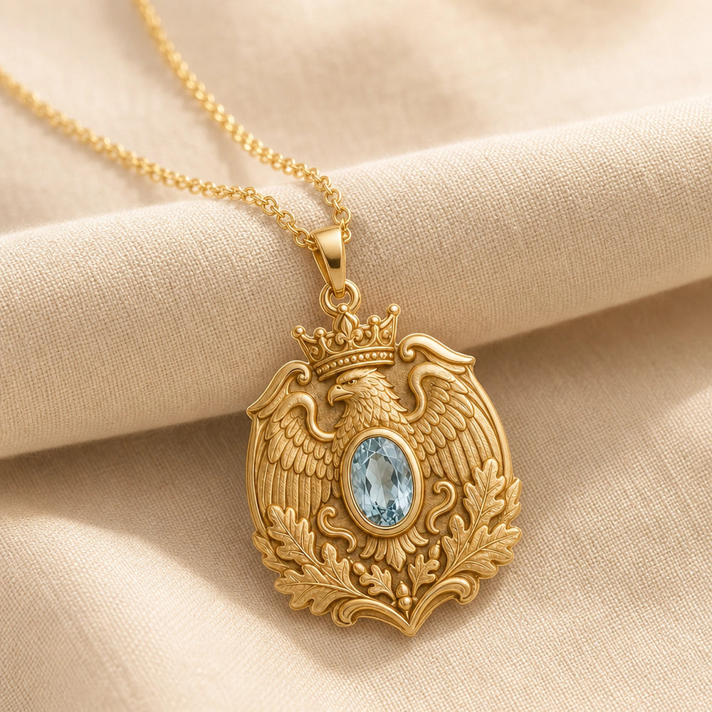 Aquamarine imperial eagle pendant with a crowned eagle, detailed feathered wings, raised oak leaves, and an oval pale-blue stone in a smooth decorative setting. Gold finish.