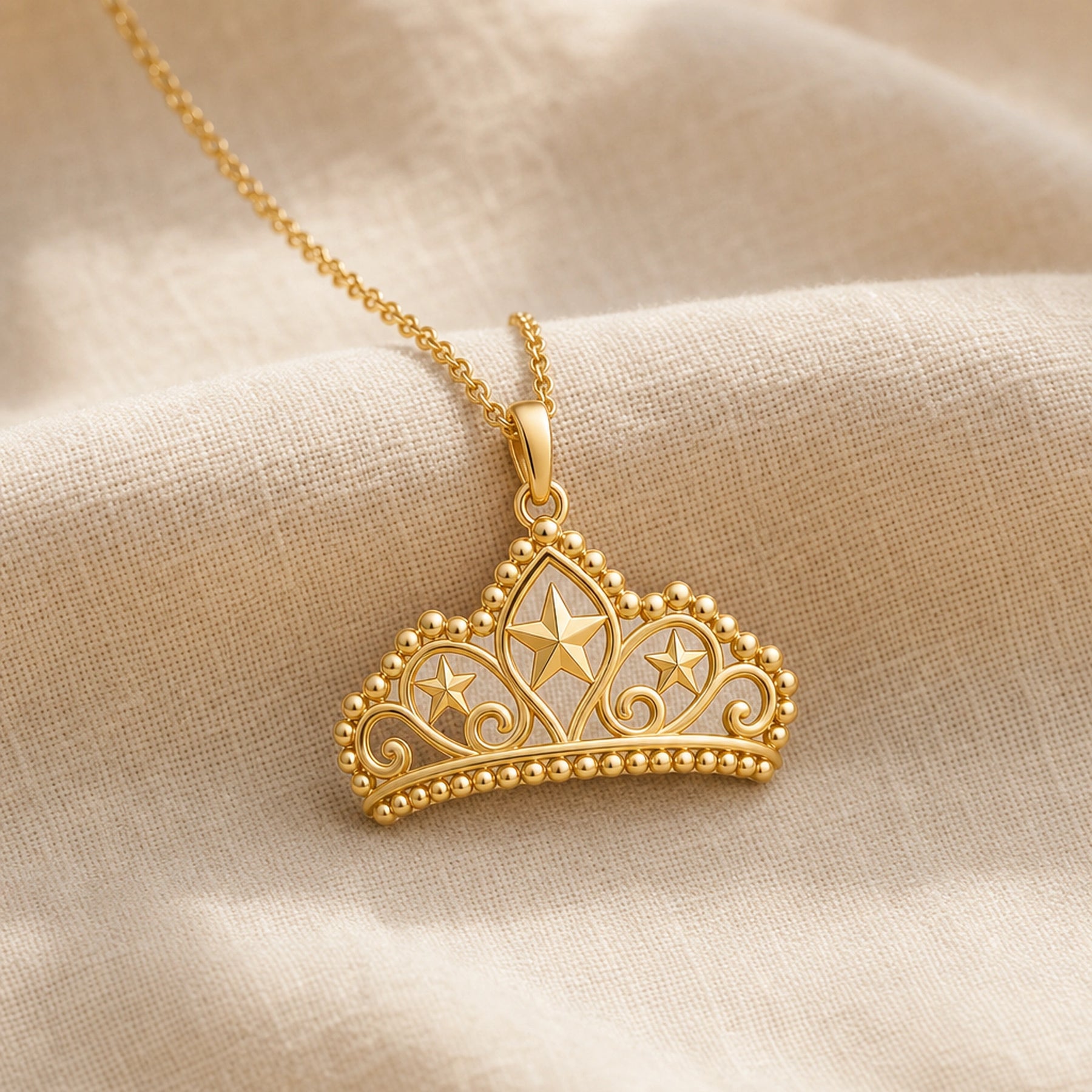 Pearl-bordered star tiara pendant with three raised star motifs, ornate openwork scrollwork, rounded bead edging, and a polished warm yellow-tone finish on a cable chain. Gold finish.