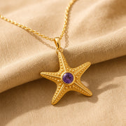 925 sterling silver five-arm starfish pendant with raised bead texture and a round purple amethyst centerpiece. Gold finish.