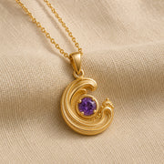 925 sterling silver wavecrest pendant curling around a round purple amethyst centerpiece with flowing textured details. Gold finish.