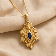 Sapphire ivy elven princess pendant with a deep blue marquise-shaped stone in a framed setting, surrounded by raised ivy leaves, curling vines, and detailed fantasy relief. Gold finish.