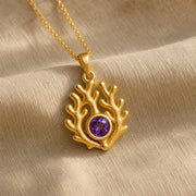 925 sterling silver branching coral pendant embracing a round purple amethyst birthstone centerpiece. Gold finish.