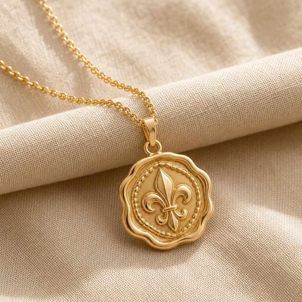 Fleur-de-lis wax seal pendant with a raised heraldic lily, beaded inner border, scalloped circular seal edge, polished warm yellow finish, and cable chain. Gold finish.