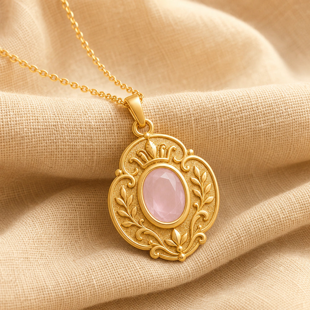 Rose quartz regal garden pendant with a faceted oval pink stone in a smooth bezel setting, surrounded by raised leaf motifs, scrollwork, and textured floral details. Gold finish.