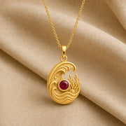 925 sterling silver tide pendant with curling ocean waves, coral and shell details, and a round ruby centerpiece. Gold finish.