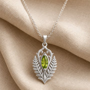Marquise peridot fern pendant with a vivid green faceted stone in a smooth setting, framed by raised elven fern leaves, openwork scrolls, and botanical relief details. Silver finish.