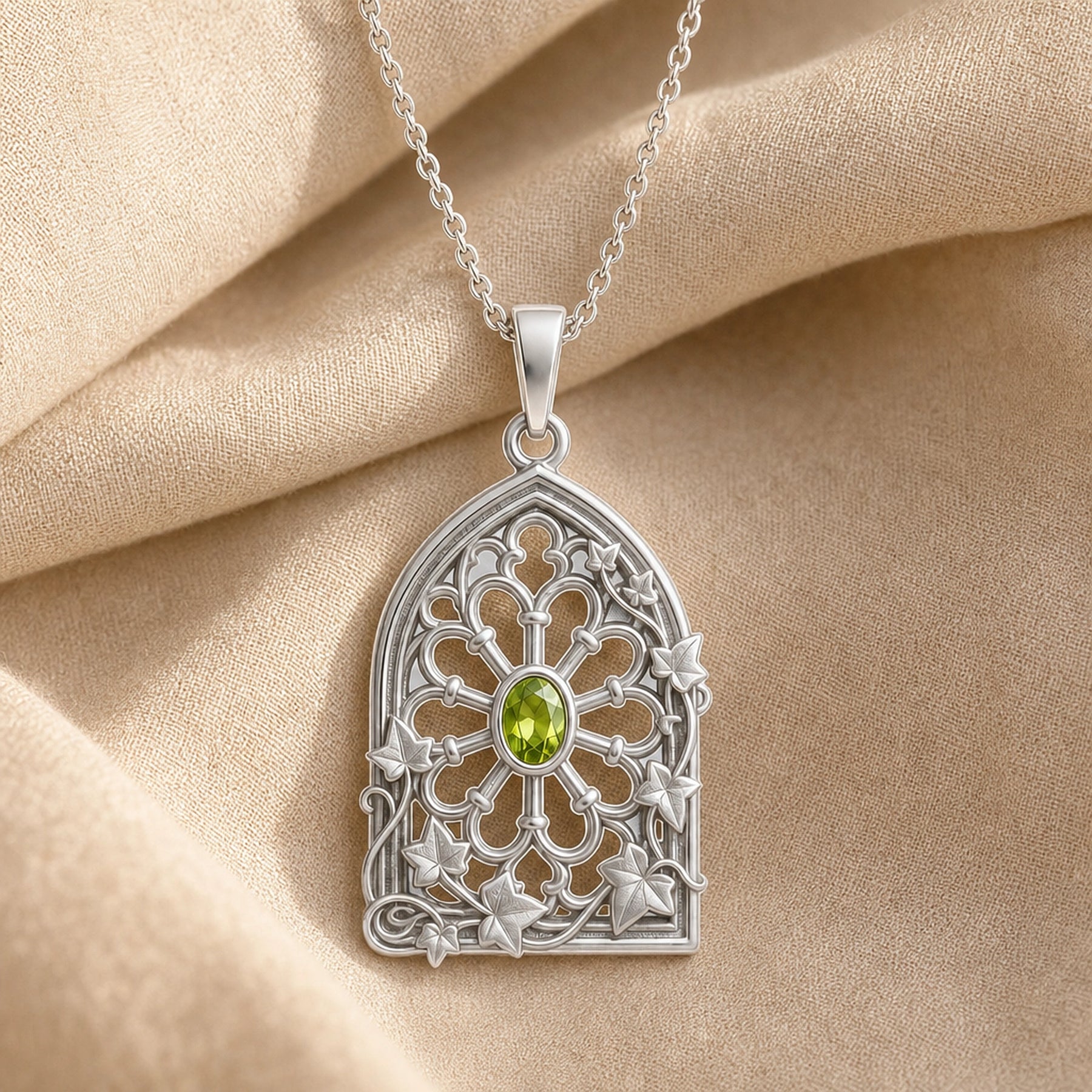 Peridot ivy rose window pendant with an oval green stone in a bezel setting, framed by openwork Gothic-style arches, floral tracery, and climbing ivy leaves. Silver finish.