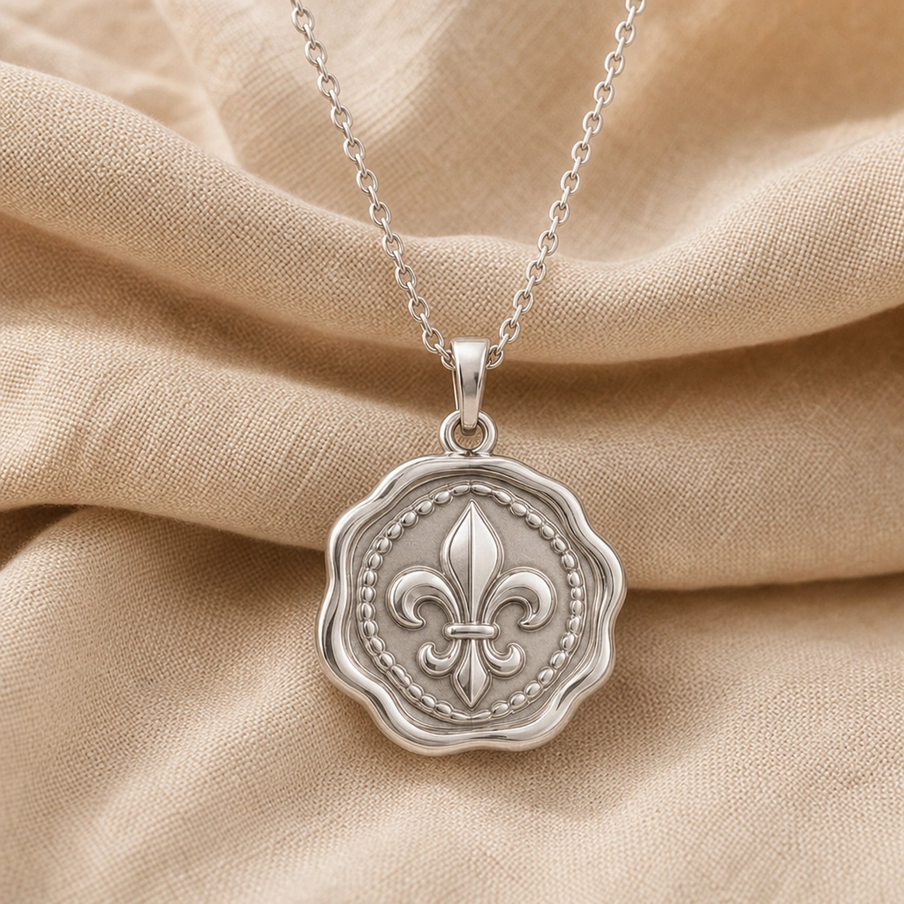 Fleur-de-lis wax seal pendant with a raised heraldic lily, beaded inner border, scalloped circular seal edge, polished warm yellow finish, and cable chain. Silver finish.