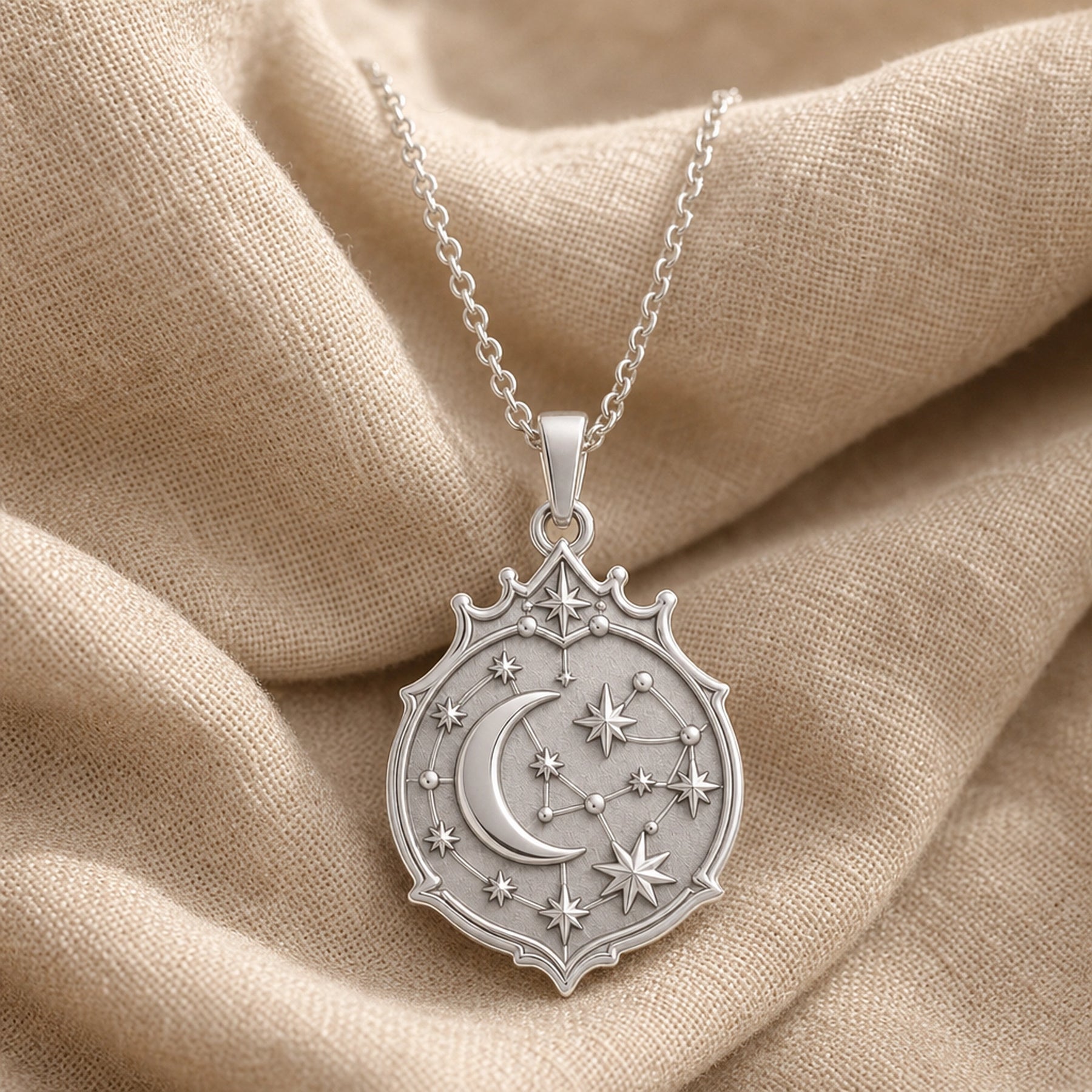 Crescent constellation pendant with raised moon, sculpted stars, orbit-like lines and an ornate celestial medallion border in 925 sterling silver. Silver finish.