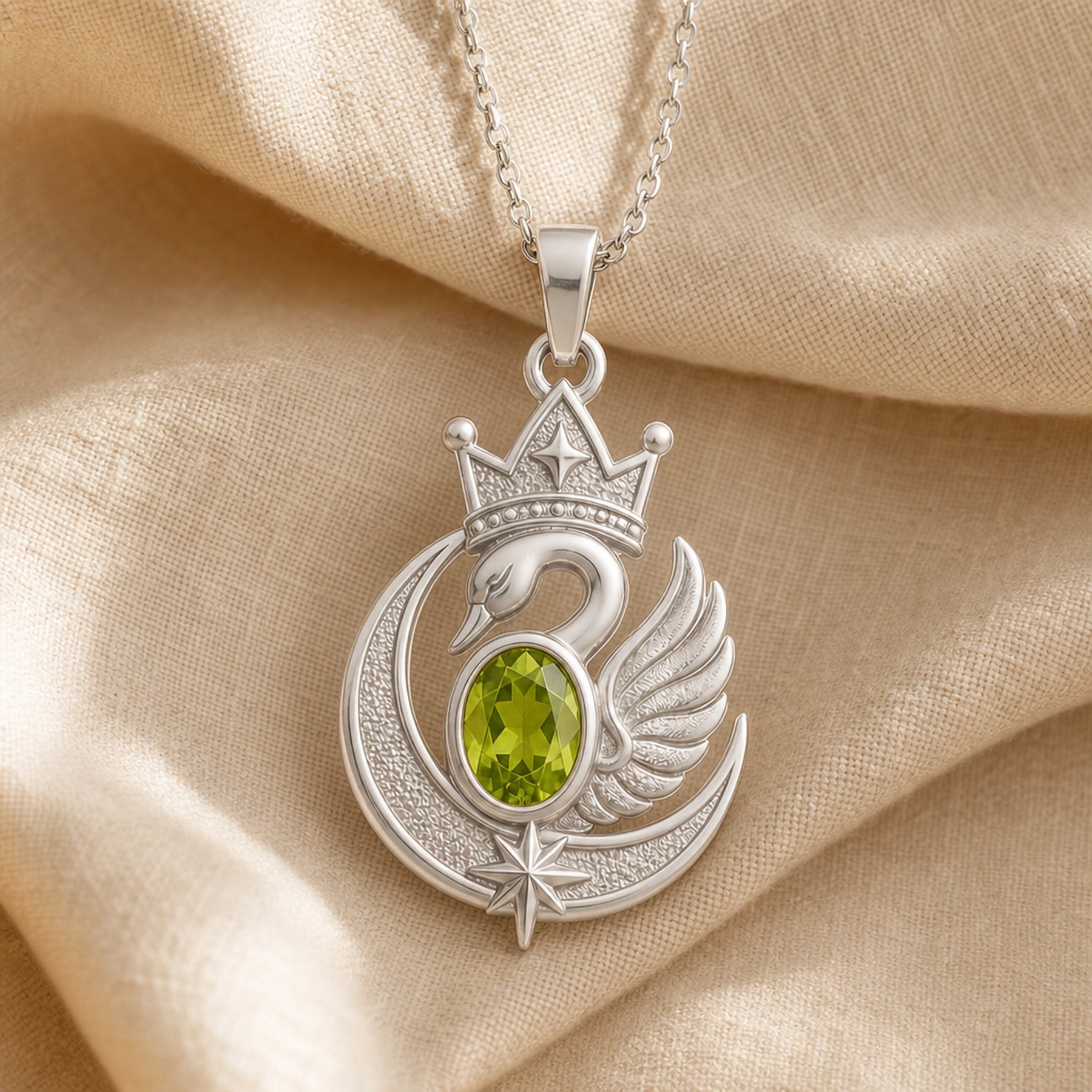 Peridot moon swan crown pendant with an oval green stone in a framed setting, detailed crowned swan, textured crescent moon, raised wing, and star accents. Silver finish.
