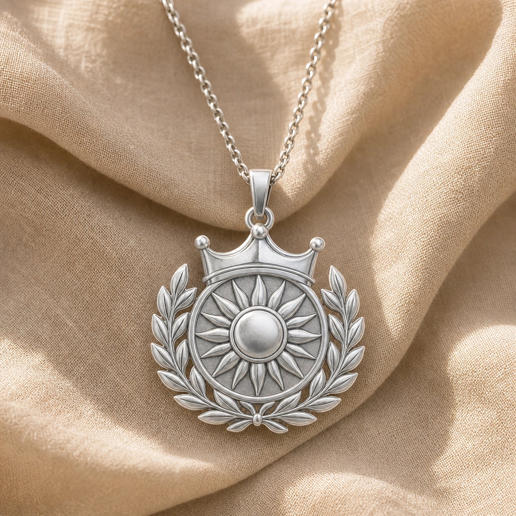 Royal sun laurel crown pendant with a raised sunburst center, polished circular medallion, detailed leaf wreath, and three-point crown on a cable chain. Silver finish.