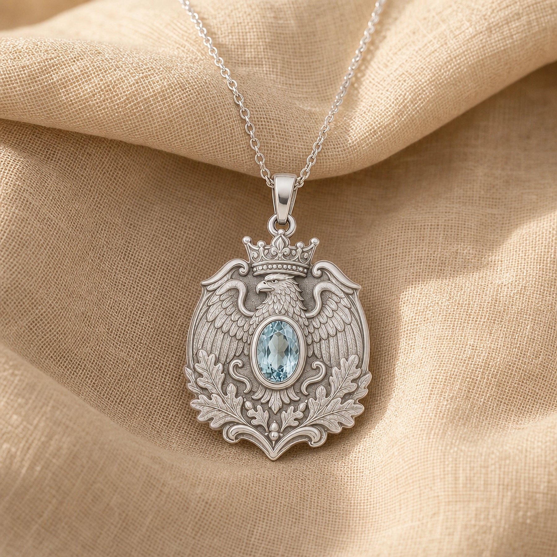 Aquamarine imperial eagle pendant with a crowned eagle, detailed feathered wings, raised oak leaves, and an oval pale-blue stone in a smooth decorative setting. Silver finish.