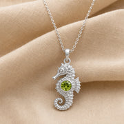 925 sterling silver seahorse pendant with a curled tail, sculpted marine details and a round green peridot centerpiece. Silver finish.