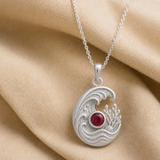 925 sterling silver tide pendant with curling ocean waves, coral and shell details, and a round ruby centerpiece. Silver finish.