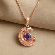 925 sterling silver wavecrest pendant curling around a round purple amethyst centerpiece with flowing textured details. Rose gold finish.