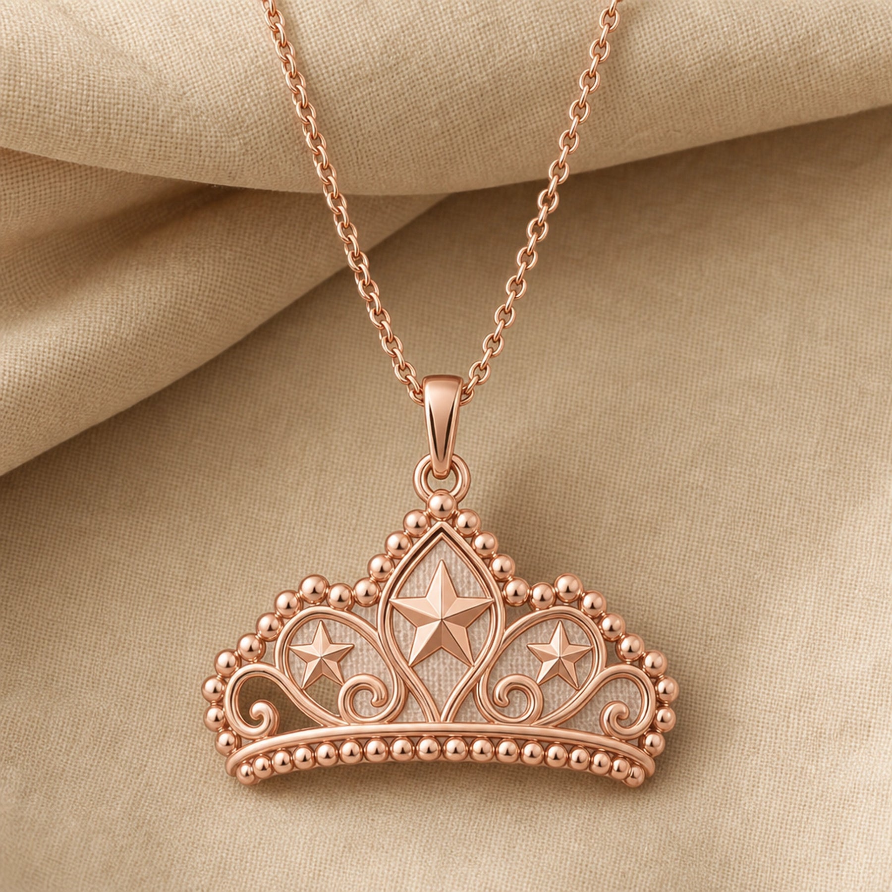Pearl-bordered star tiara pendant with three raised star motifs, ornate openwork scrollwork, rounded bead edging, and a polished warm yellow-tone finish on a cable chain. Rose gold finish.