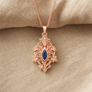 Sapphire ivy elven princess pendant with a deep blue marquise-shaped stone in a framed setting, surrounded by raised ivy leaves, curling vines, and detailed fantasy relief. Rose gold finish.