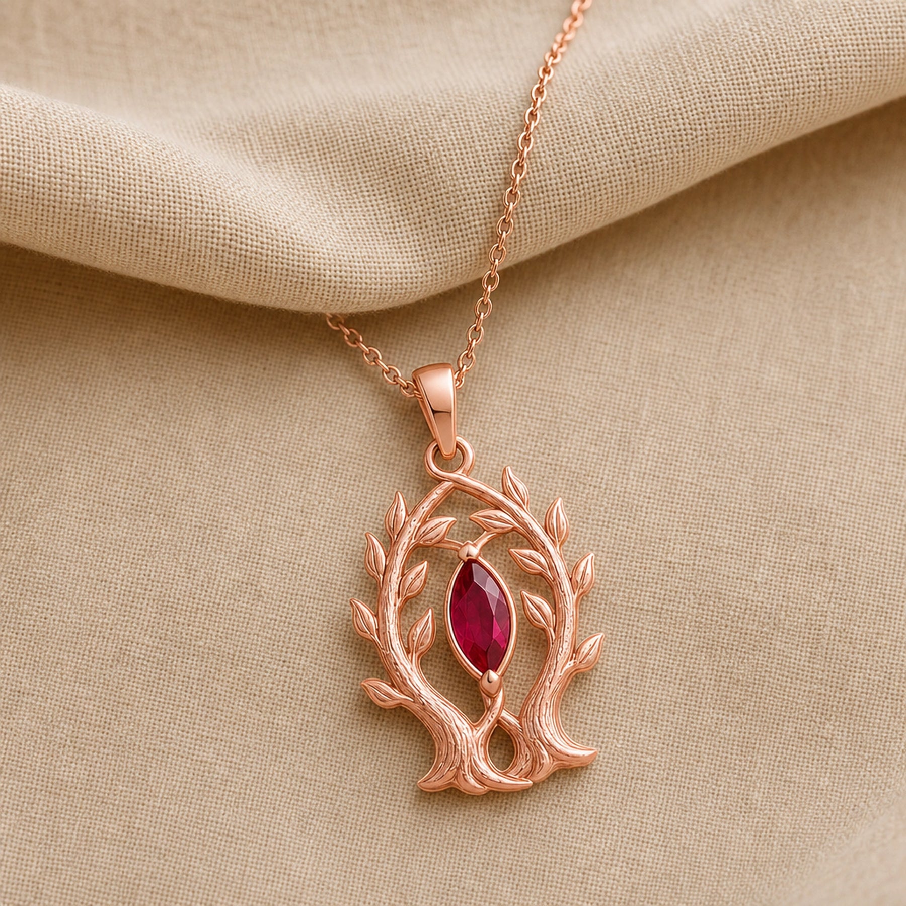 Marquise ruby branch pendant in 925 sterling silver, featuring a deep red faceted marquise stone held in a leaf-tipped openwork tree frame. Rose gold finish.