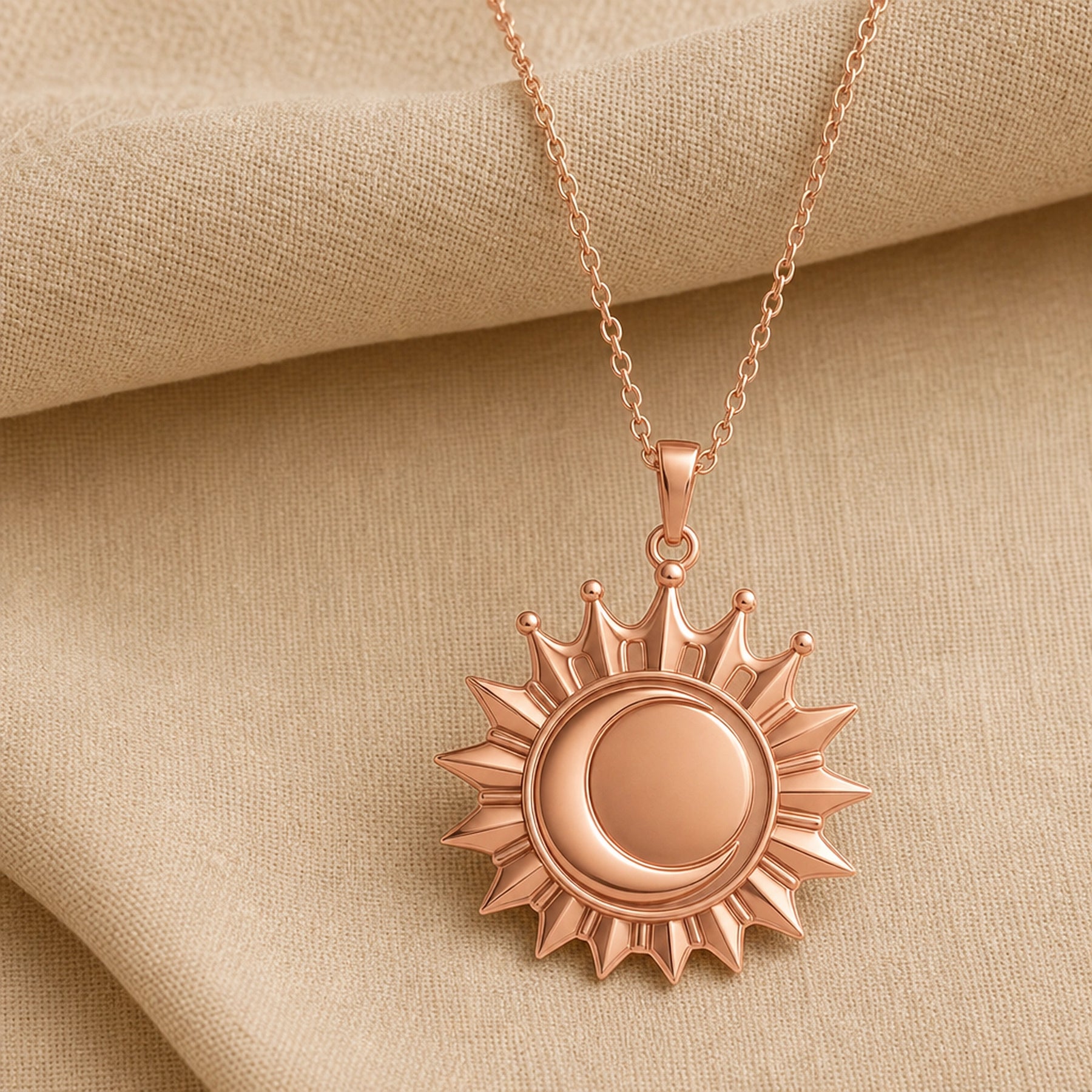Regal eclipse sunray crown pendant with a raised circular center, pointed radiant rays, crown-like arches, and polished warm yellow finish on a cable chain. Rose gold finish.