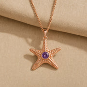 925 sterling silver five-arm starfish pendant with raised bead texture and a round purple amethyst centerpiece. Rose gold finish.