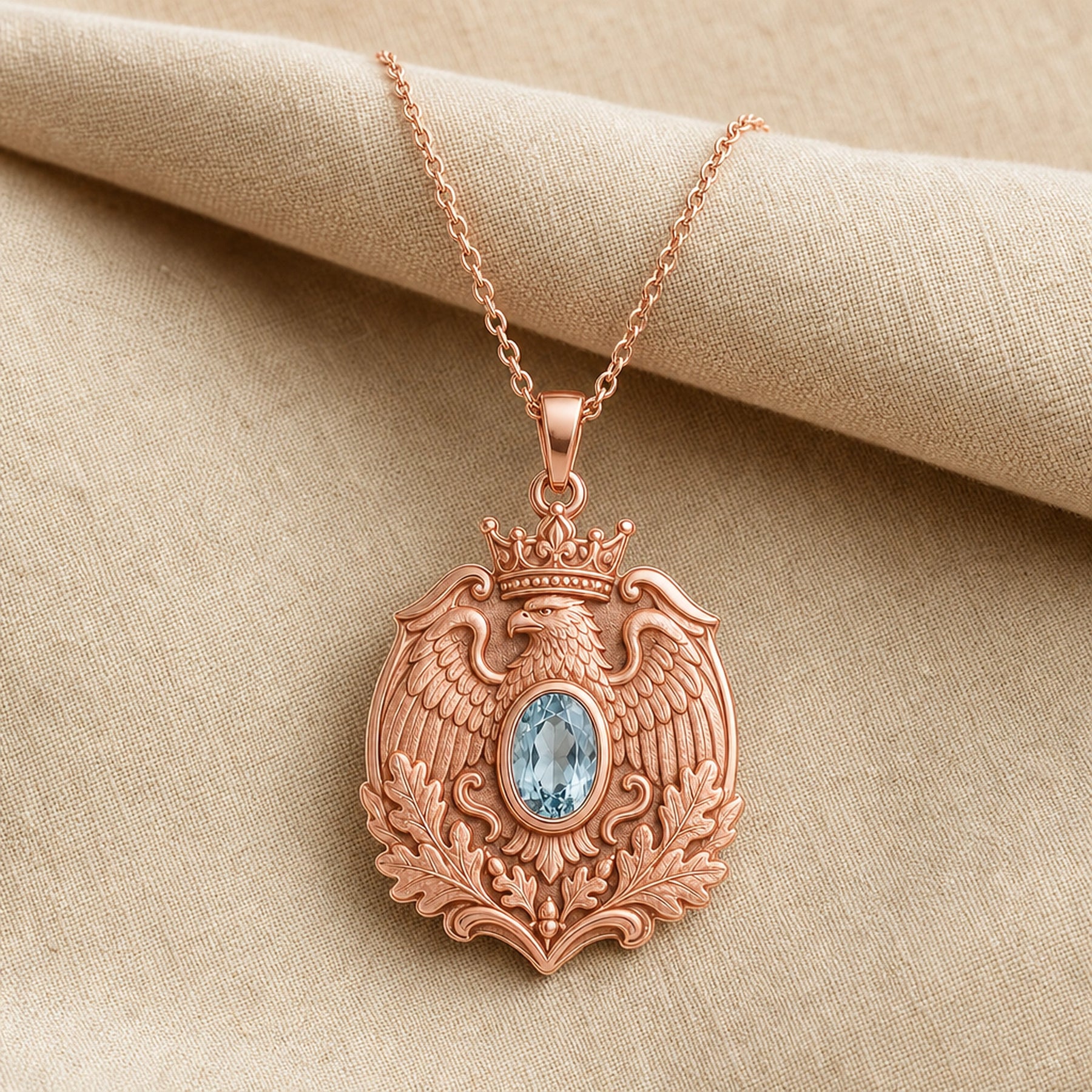 Aquamarine imperial eagle pendant with a crowned eagle, detailed feathered wings, raised oak leaves, and an oval pale-blue stone in a smooth decorative setting. Rose gold finish.