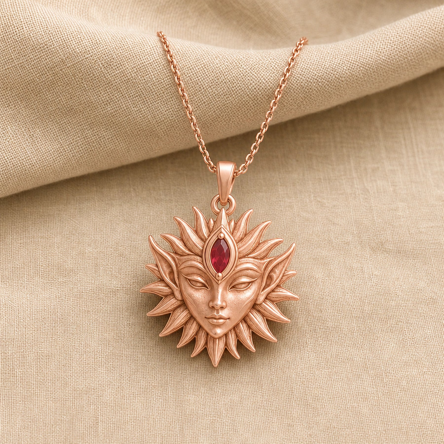 Marquise ruby sun elf pendant with a detailed sculpted elf face, radiating sun rays, and a deep red marquise stone set at the center of the forehead. Rose gold finish.