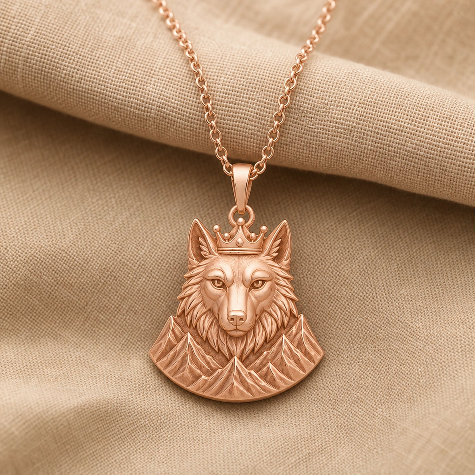 Crowned alpine wolf pendant in a warm yellow finish, showing a detailed wolf head, raised crown, and sculpted mountain relief beneath the bail. Rose gold finish.