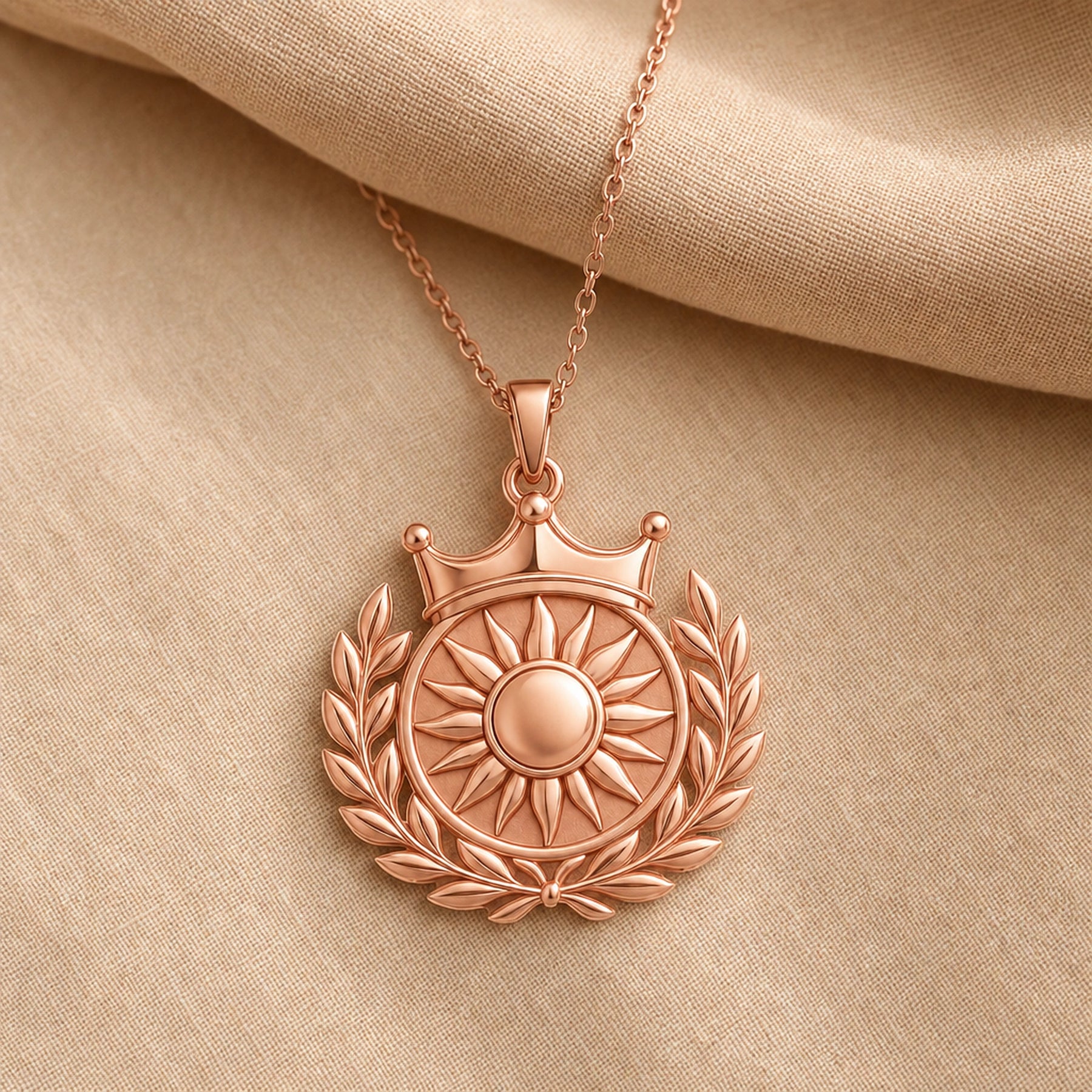 Royal sun laurel crown pendant with a raised sunburst center, polished circular medallion, detailed leaf wreath, and three-point crown on a cable chain. Rose gold finish.