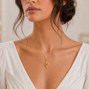Ruby trident pendant necklace in 925 sterling silver with curved three-pronged relief design and a round vivid red center stone in a bezel-style setting. Worn on a model, front view.
