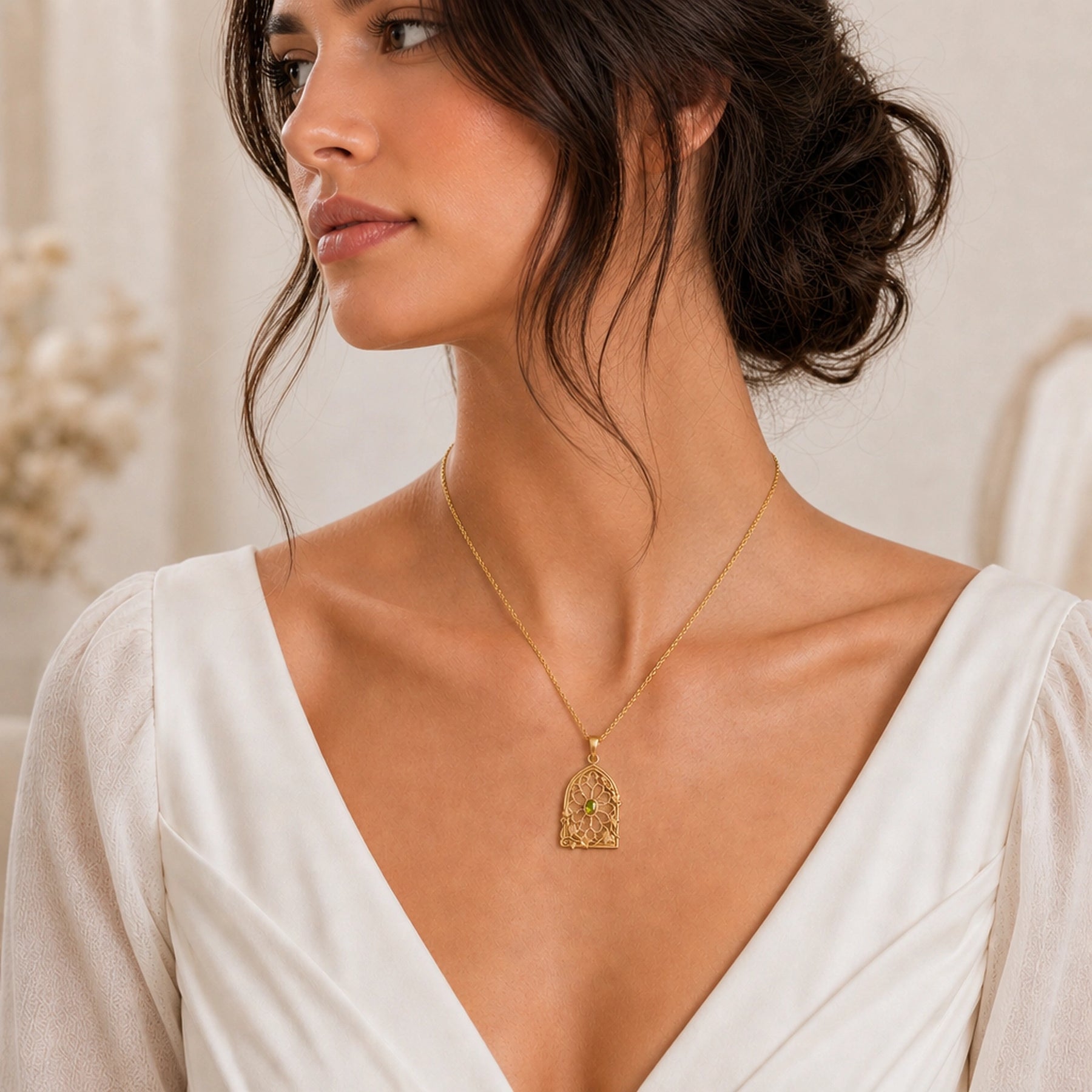 Peridot ivy rose window pendant with an oval green stone in a bezel setting, framed by openwork Gothic-style arches, floral tracery, and climbing ivy leaves. Worn on a model, angled view.