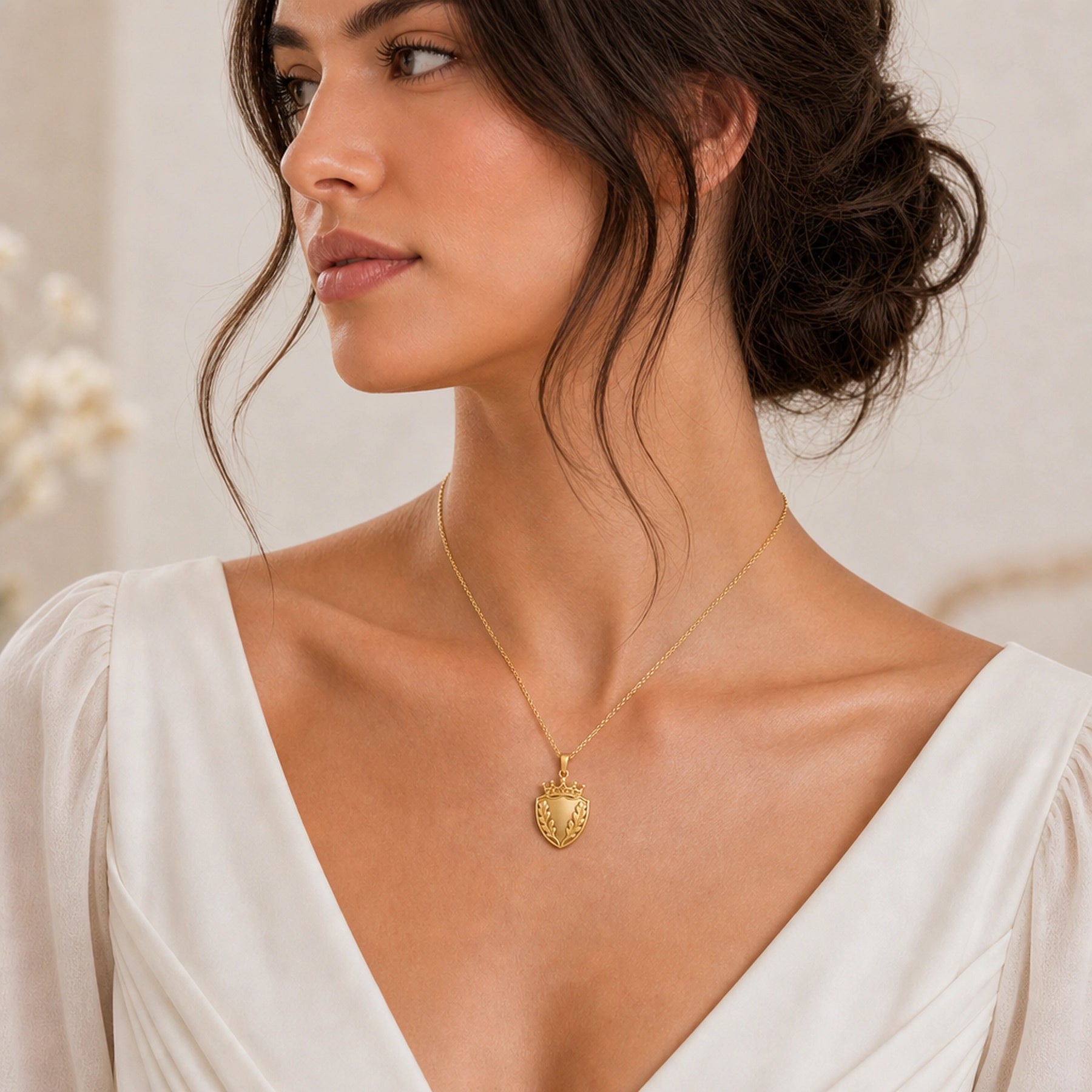 Oakleaf crown shield pendant with a pointed shield shape, raised botanical leaf relief, detailed crown top, smooth center panel, and a polished cable chain. Worn on a model, angled view.